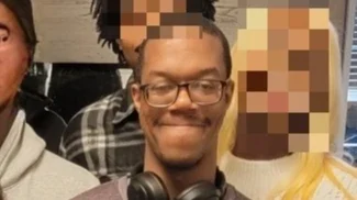 Brian Cole Jr. wearing glasses and headphones around his neck in the family campaign photograph; some surrounding faces are pixelated in the source